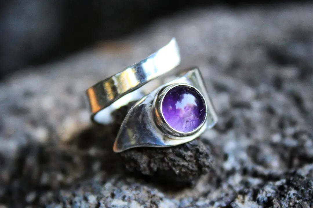 Colgante de obsidiana negra con ojo de tigre facetado, envuelto en alambre de plata retorcido.